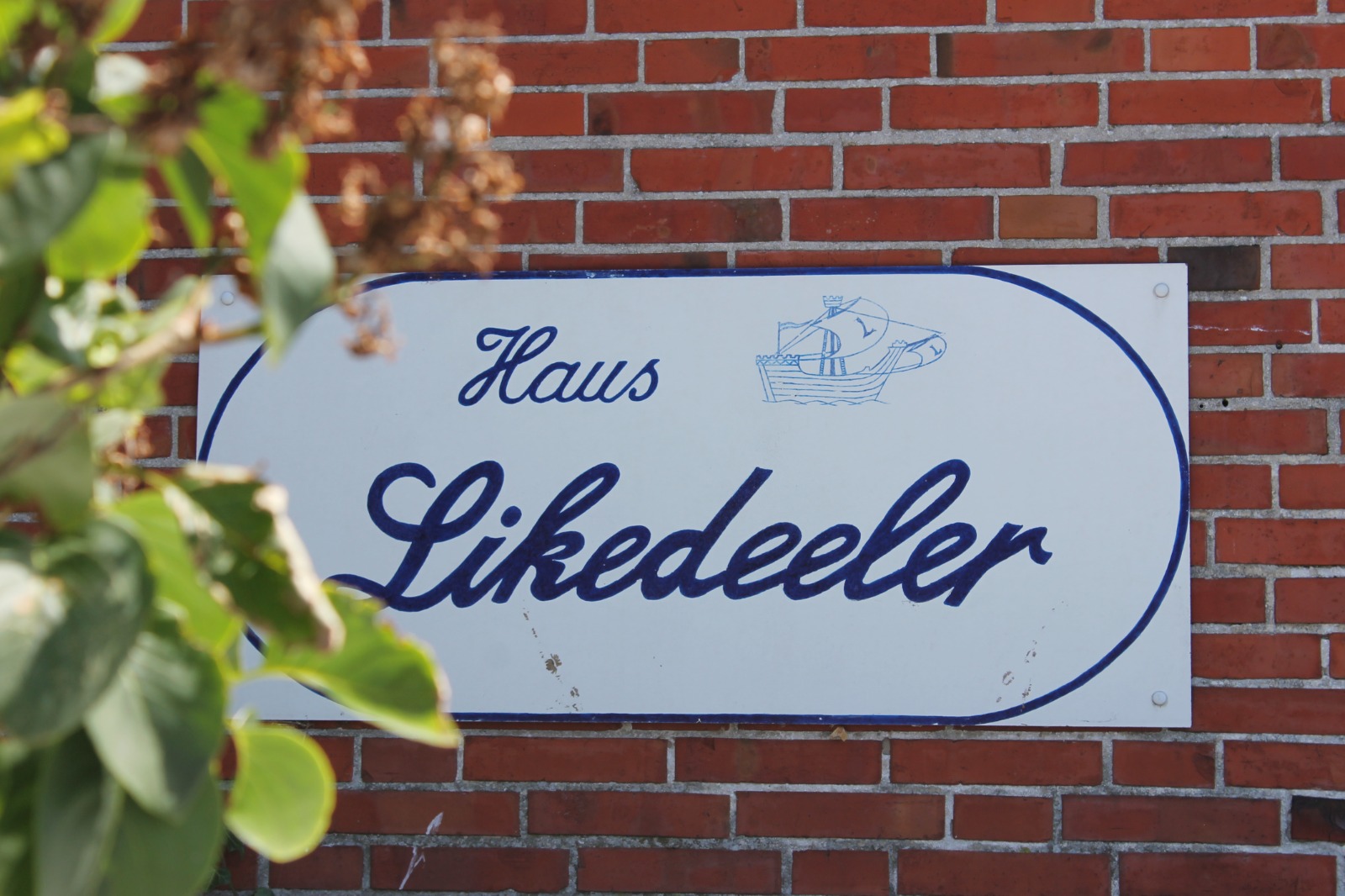 Hausschild 'Haus Likedeeler' mit handgezeichnetem Segelschiff, an der Backsteinwand des Hauses